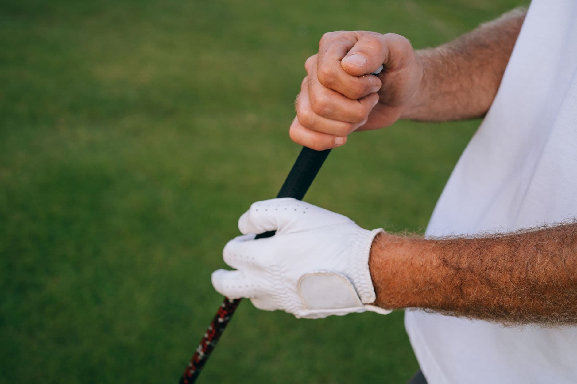 A golfer's gloved hands gripping a club on the course